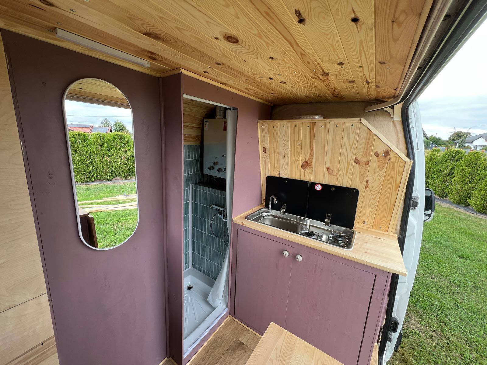 Campervan med lilla kjøkkeninnredning, trepanel og kompakt dusjrom