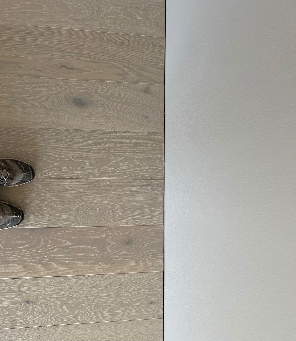 Detalj av hvit gulvlist mot lyst gulv